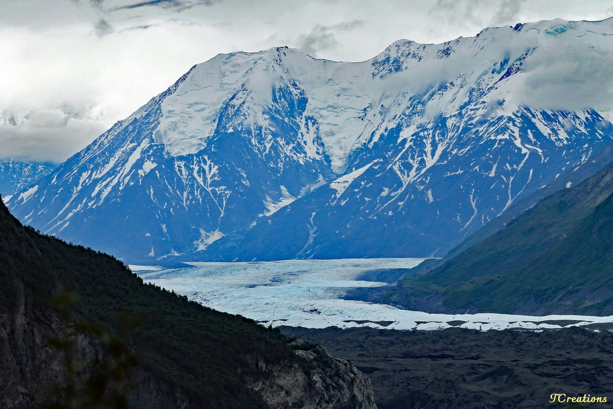 A glacier winding between snow covered mountains